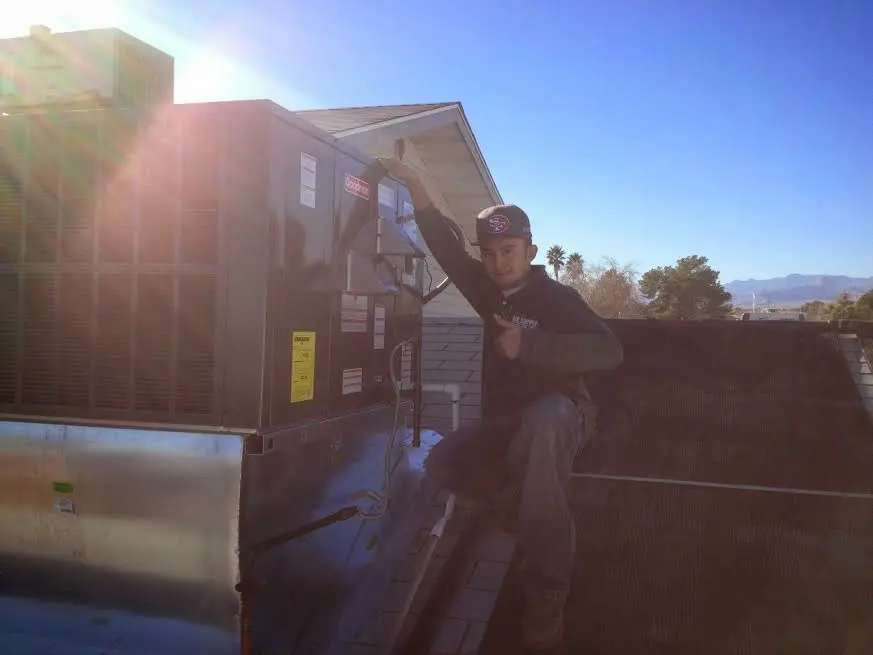 HVAC technician performing AC Tune-Up on a rooftop unit in Ross